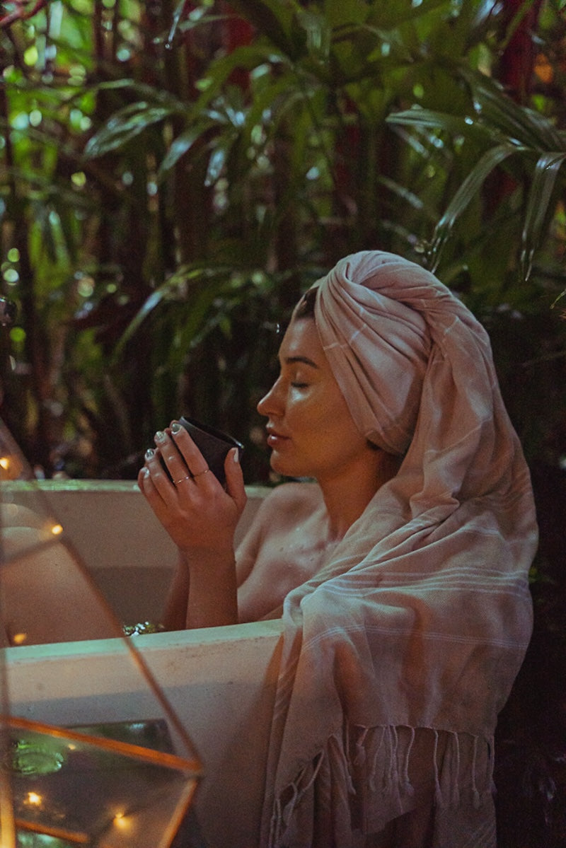 Beige color Wetcat Turkish towel is wrapped on a woman's head who is taking a relaxing bath