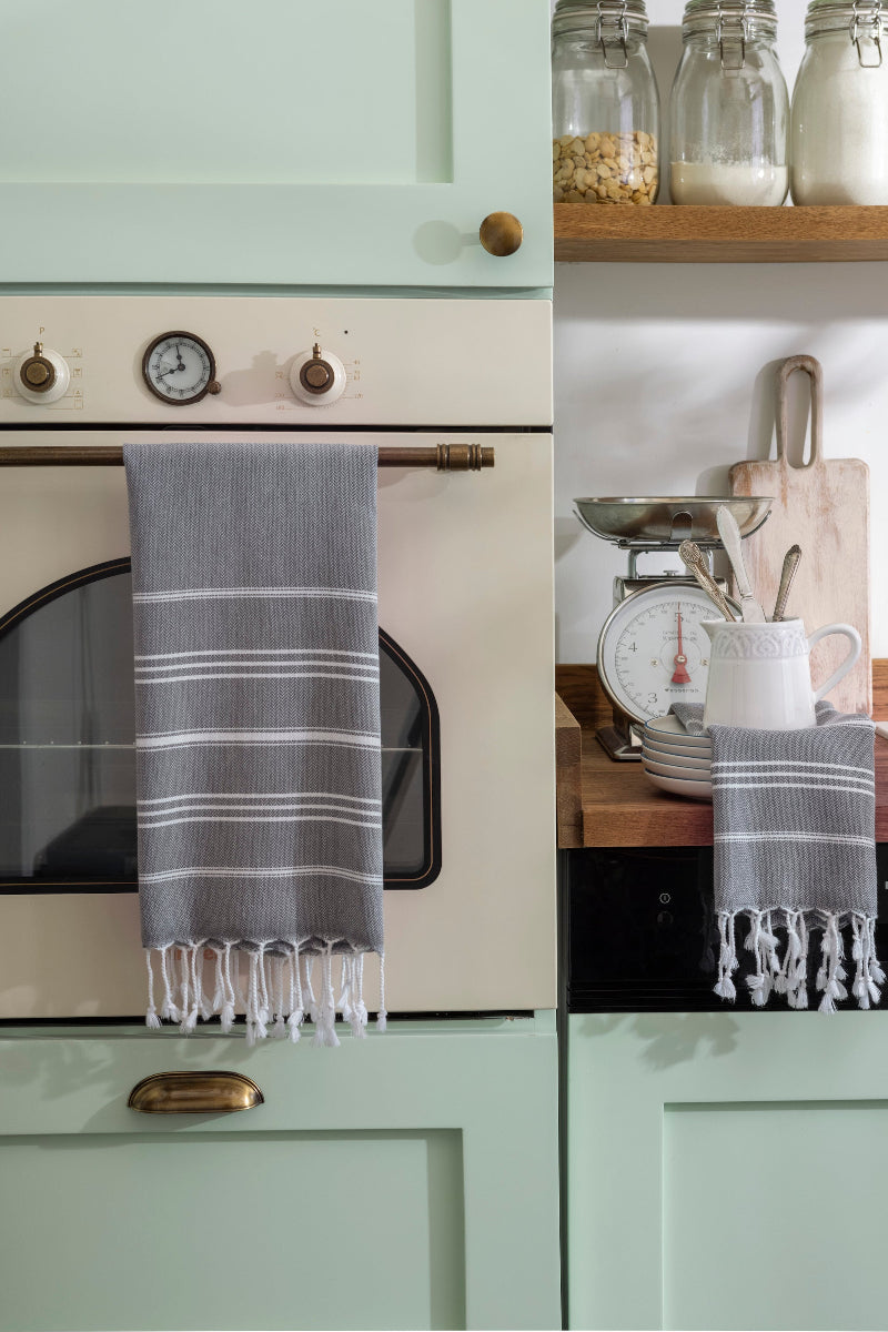 Dark gray Wetcat Turkish hand towels are hung on the oven's handle 