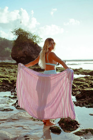 A woman traveler in Bali holding a lilac Turkish towel out